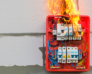 Red electrical panel on a wall, with flames coming out of it. Emergency Electrical Services